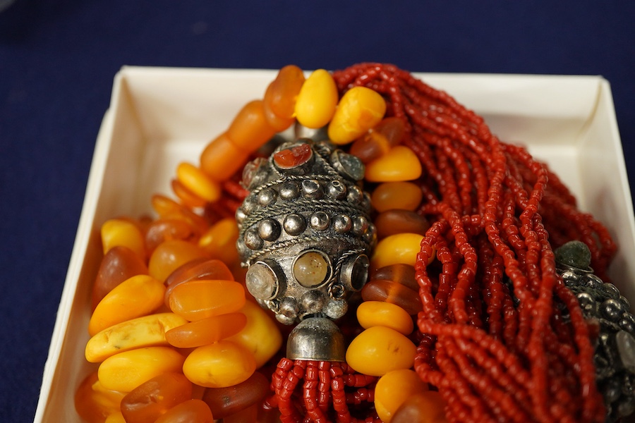 Two necklaces, comprising: a multi-strand coral necklace of torsade design, spaced by beads set with various hardstones, length 73cm; and an amber bead necklace, length 57cm